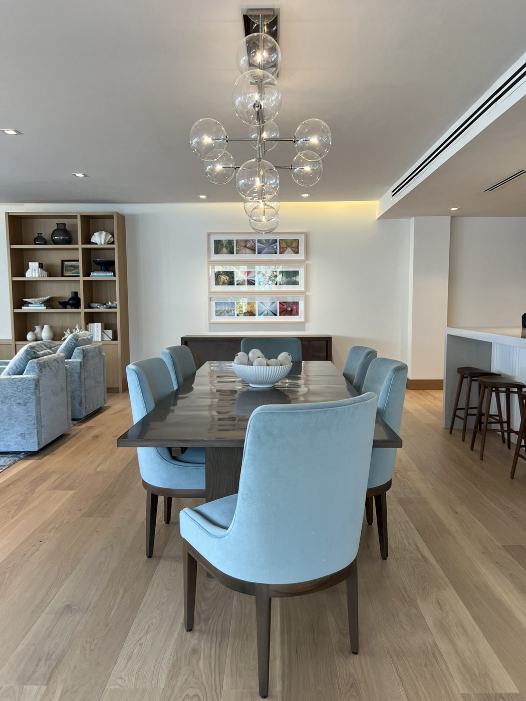 Dining room with blue velvet chairs, a dark wood table and a glass globe chandelier