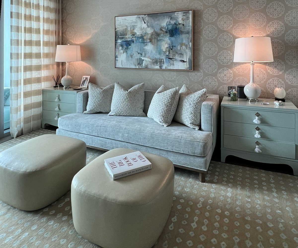 Home office lounge with a pale blue daybed, abstract art, celadon chests with tassel pulls, patterned grasscloth and leather ottomans